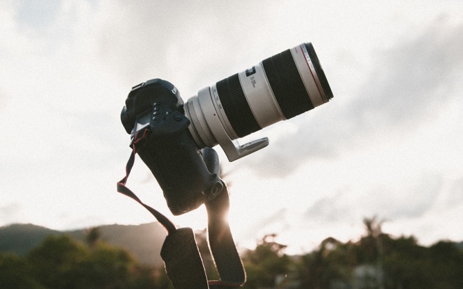 A camera sitting in the open with a sunset in the background