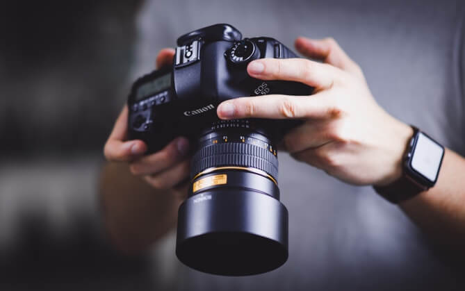 A persons hands holding a camera
