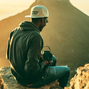 A person sitting on a rock holing a camera
